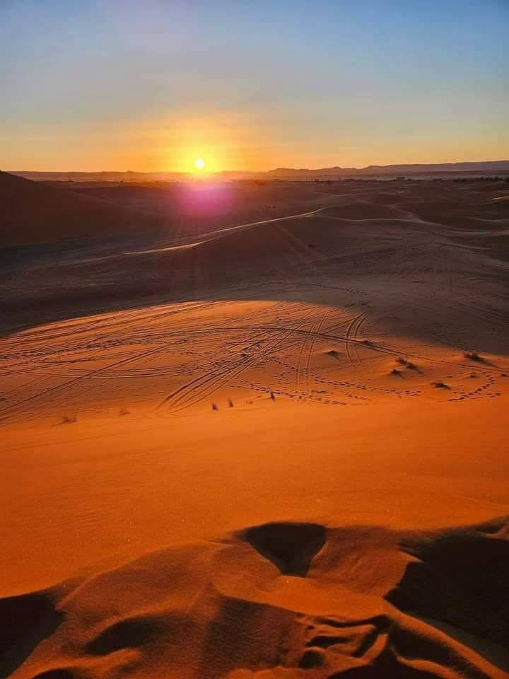 Soleil couchant sur les dunes, traces dans le sable orange
